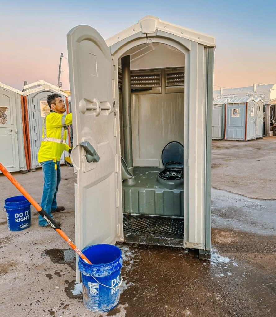 desert services employee washing portable toilet